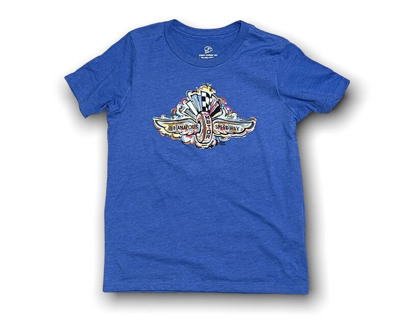 Puede incluir: Una camiseta azul real con un gr&aacute;fico colorido del logotipo del Indianapolis Motor Speedway. El logotipo presenta una rueda alada estilizada con las palabras "Indianapolis Motor Speedway" alrededor.