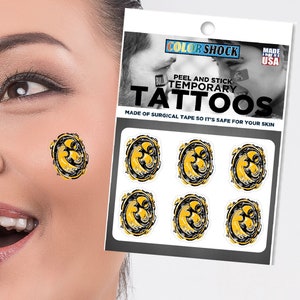 May include: A sheet of temporary tattoos with a yellow and black design. The sheet says "Color Shock Peel and Stick Temporary Tattoos" and "Made of surgical tape so it's safe for your skin".