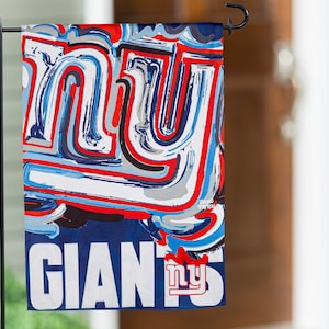 May include: A blue and red garden flag with the word "NY" in a stylized font and the word "GIANTS" in white letters below. The "NY" is in a blue and red swirl pattern.