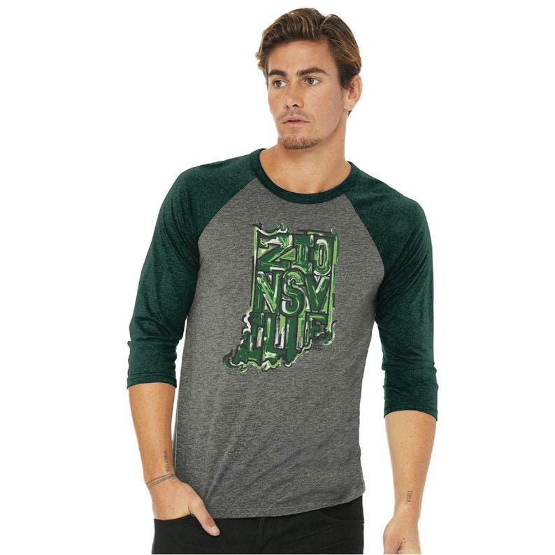 May include: A heather grey and forest green baseball tee shirt with a graphic of the state of Indiana. The graphic is made up of the words "Zionsville" in a green camouflage pattern.