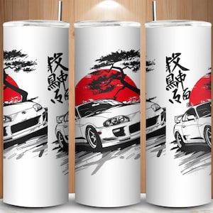 May include: White tumbler featuring a Japanese-inspired design. The design includes a white sports car, a red sun, a black tree, and Japanese calligraphy. The tumbler is cylindrical and has a silver lid.
