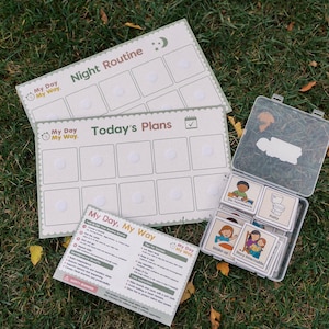May include: A set of organisational tools for daily and nightly routines. Includes a "Night Routine" and "Today's Plans" board, a card set, and a guide, all with the "My Day, My Way" branding. The items are arranged on a bed of green grass.
