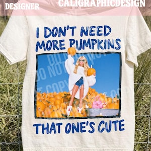 May include: A cream-colored t-shirt featuring the blue text I DON'T NEED MORE PUMPKINS THAT ONE'S CUTE. The center graphic shows a blonde doll wearing a white sweater, blue denim shorts, and sunglasses, holding two orange pumpkins in a pumpkin patch.