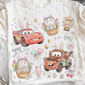 Può includere: T-shirt bianca con illustrazioni di cartoni animati di Saetta McQueen e Cricchetto del film Cars, decorata con elementi a tema pasquale come orecchie da coniglio, uova di Pasqua e cesti di fiori. Include un trofeo e fiocchi.