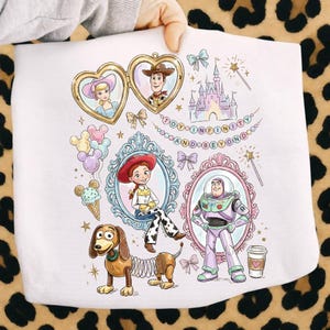 Może przedstawiać: Biała tkanina z ilustracjami postaci z Toy Story, w tym Woody, Buzz Lightyear i Jessie, w ozdobnych ramkach. Zawiera r&oacute;wnież napis "TO INFINITY AND BEYOND".