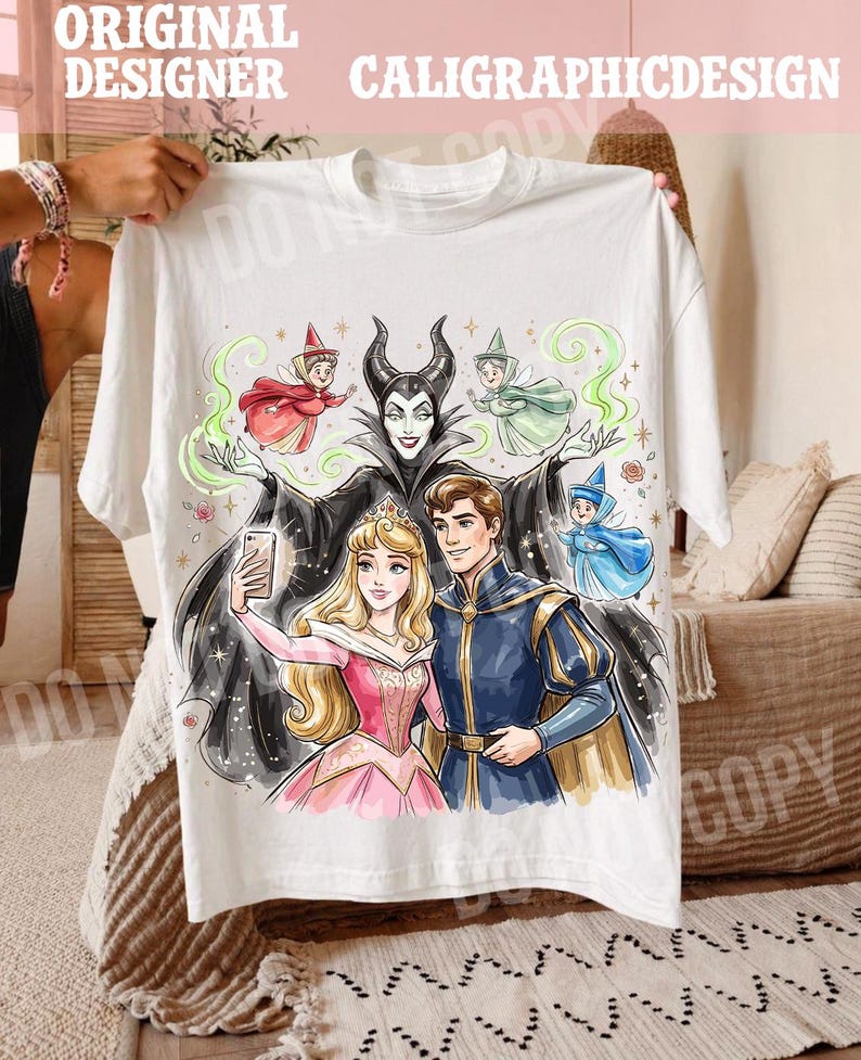 May include: White t-shirt with a vibrant illustration of fairy tale characters. The design includes a princess, a prince, and a villain, along with several fairies. The text "ORIGINAL DESIGNER CALIGRAPHICDESIGN" is printed at the top.