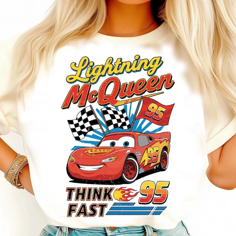 May include: White t-shirt featuring Lightning McQueen from the Cars movie. The design includes the text "Lightning McQueen" in yellow and red, the number "95", and the phrase "Think Fast". Checkered flags and a red race car are also featured.