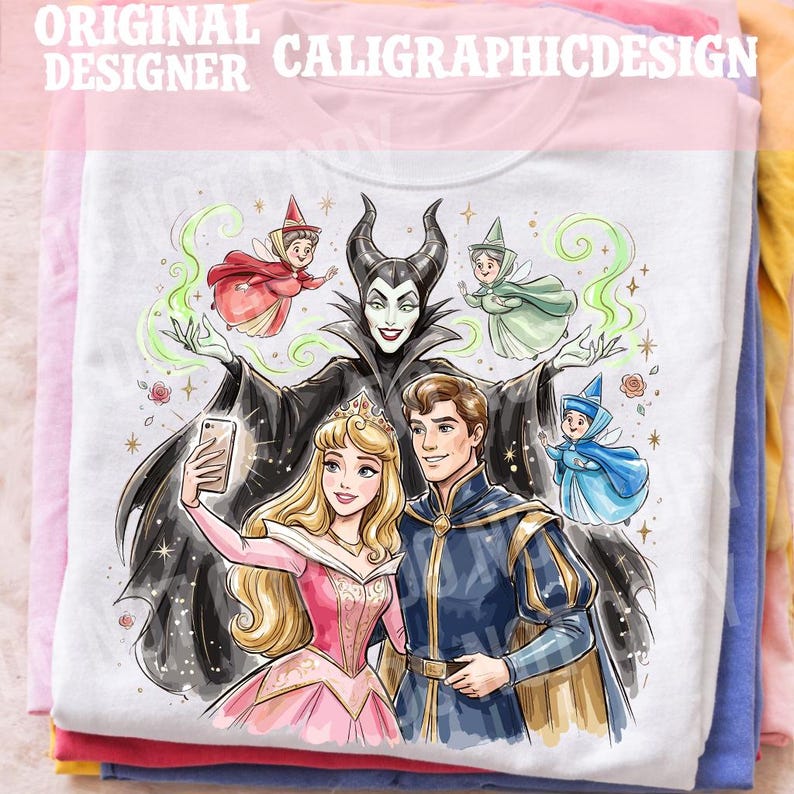 May include: White t-shirt with a cartoon illustration of Princess Aurora, Prince Phillip, and Maleficent taking a selfie. The design includes fairies and the text "ORIGINAL DESIGNER CALIGRAPHICDESIGN". The shirt is folded with other colourful shirts.