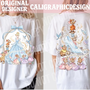 May include: White t-shirt featuring a Cinderella-themed design. The front shows Cinderella in a blue gown with mice and birds. The back displays a glass slipper, mice, and sewing elements. The text "ORIGINAL DESIGNER CALIGRAPHICDESIGN" is at the top.