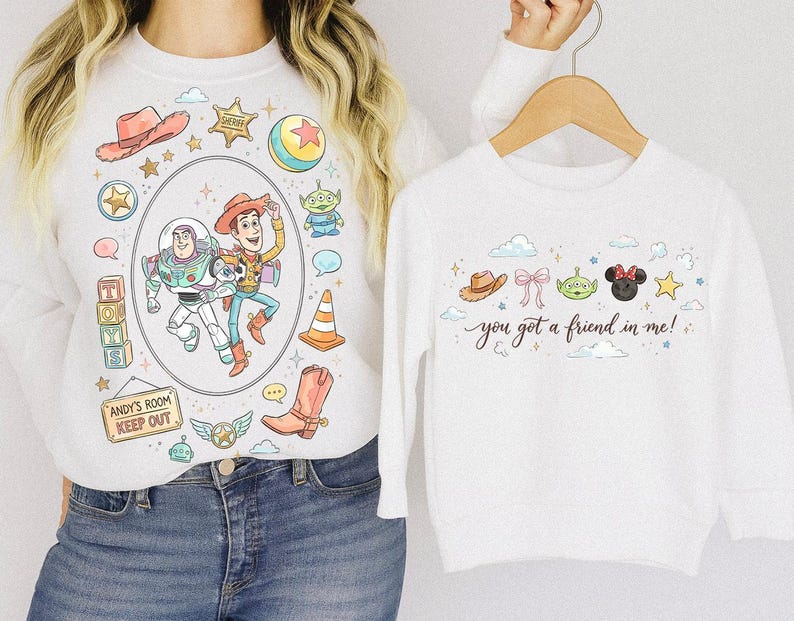 May include: White sweatshirts with colorful Toy Story graphics. One sweatshirt features Buzz Lightyear and Woody in an oval frame, surrounded by other Toy Story elements. The other sweatshirt has the text "you got a friend in me!" with other Toy Story characters.