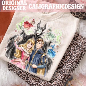 May include: Cream-coloured t-shirt with a colourful illustration of fairy tale characters. The design includes a princess, a prince, fairies, and a villain taking a selfie. The text "ORIGINAL DESIGNER CALIGRAPHICDESIGN" is at the top.