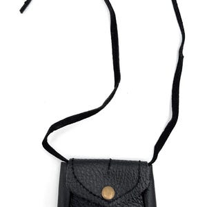 May include: A small, black leather pouch with a flap closure and a brass button. The pouch has a textured surface and is suspended by a black cord. The design is simple and classic, suitable for carrying small items.