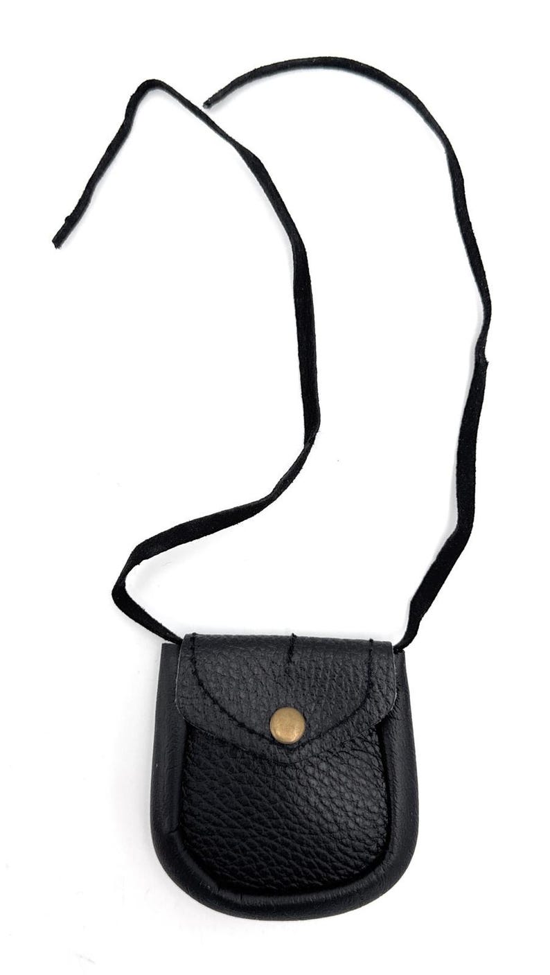 May include: A small, black leather pouch with a flap closure and a brass button. The pouch has a textured surface and is suspended by a black cord. The design is simple and classic, suitable for carrying small items.