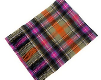 May include: A colorful plaid scarf with a fringed edge. The scarf features a pattern of intersecting lines in shades of pink, orange, black, and green. The fringed edge has strands of black, pink, and orange.