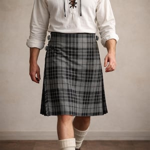 May include: A gray and black plaid kilt with a fringed edge. The kilt is secured with buckles and is worn with a white shirt with a laced neckline. The kilt is a traditional garment.