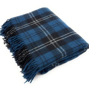 May include: A folded blue plaid blanket with fringe. The blanket features a classic tartan pattern in shades of blue, black, and white. The fringe is a darker blue and black. The blanket is made of a soft, woven material.