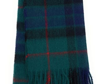 May include: A green, blue, and black plaid scarf with red accents and fringe. The scarf is made of a soft material and is folded in half. The scarf is approximately 60 inches long.