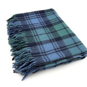 Op de afbeelding: Gevouwen blauw, groen en marineblauw geruite deken met gefranjerde randen. De deken heeft een klassiek tartanpatroon, perfect om een vleugje warmte en stijl aan elke ruimte toe te voegen. De zachte textuur en het kleurenpalet maken het een gezellig woonaccessoire.
