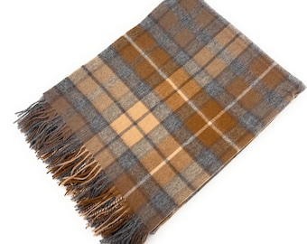 May include: A rectangular blanket with a plaid pattern in shades of brown, tan, and gray. The blanket has a fringed edge in matching colors. The design features a classic tartan pattern, suitable for home decor.