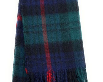May include: A folded scarf with a classic plaid pattern. The scarf features a combination of navy blue, green, and black with red accents. The scarf has a fringed edge. This accessory is suitable for cold weather.