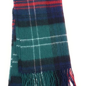 May include: A tartan scarf in teal, navy, and red. The scarf has a classic plaid design with white lines and fringed edges. The scarf is made of a soft, woven material. The scarf measures approximately 180 cm in length.