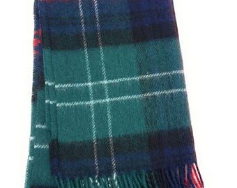 May include: A tartan scarf in teal, navy, and red. The scarf has a classic plaid design with white lines and fringed edges. The scarf is made of a soft, woven material. The scarf measures approximately 180 cm in length.
