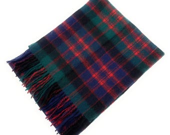 May include: A rectangular scarf with a classic plaid pattern in shades of red, green, blue, and black. The scarf has fringed edges in red, blue, and green. The scarf is displayed on a white background.