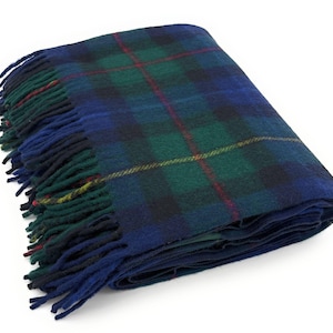 May include: A folded tartan blanket in blue, green, and red. The blanket has a traditional plaid design with fringed edges. The colours are deep and rich, creating a cosy feel. The blanket is made of a soft, woven material, perfect for adding warmth.