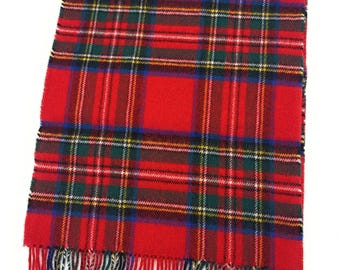 May include: A red plaid scarf with a fringed edge. The scarf features a classic tartan pattern in red, green, blue, yellow, and white. The fringed edge adds a decorative touch to this winter accessory.