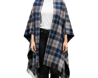 May include: A blue, gray, and red plaid cape with a fringed hem. The cape is draped over a person wearing a white shirt and black pants. The plaid pattern is a classic design.