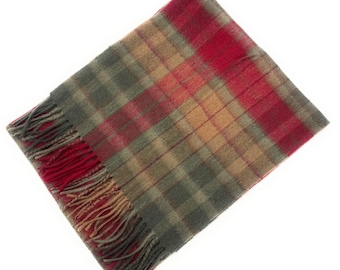 May include: A rectangular scarf with a plaid pattern in shades of red, green, and tan. The scarf has a fringed edge in red and tan. The fabric appears to be soft and warm, suitable for cold weather.