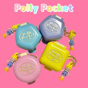 Może przedstawiać: Cztery zabytkowe kompakty Polly Pocket w kolorze niebieskim, fioletowym, ż&oacute;łtym i r&oacute;żowym, każdy z dołączoną miniaturową lalką. Logo Polly Pocket jest widoczne na każdym kompakcie na r&oacute;żowym tle.