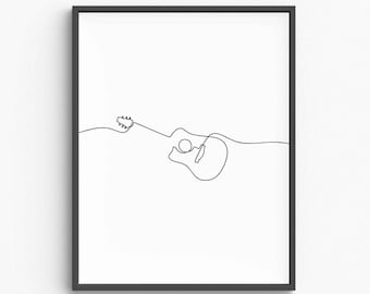 May include: A framed minimalist art print featuring a continuous line drawing of an acoustic guitar in black against a white background. The guitar's outline includes the headstock, body, and sound hole. The artwork is encased in a black frame.
