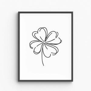 Op de afbeelding: Ingelijste kunstdruk met een minimalistische zwarte lijntekening van een klavertjevier. Het kunstwerk heeft een witte achtergrond en een eenvoudig, elegant ontwerp. De klaver is afgebeeld met delicate, gebogen lijnen.