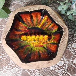 May include: A hexagonal bowl with a light brown wood-grain textured exterior and a glossy interior featuring a vibrant, swirling abstract pattern in shades of deep red, bright yellow, and lime green, centered around a cluster of yellow textured bumps.