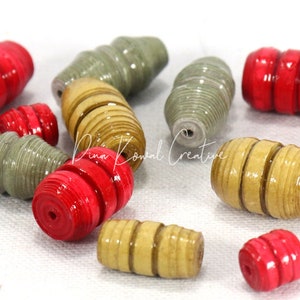 May include: A collection of colorful paper beads in red, beige, and green. The beads are made of rolled paper and have a spiral design.