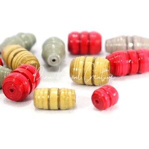 May include: A collection of colorful paper beads in red, gold, and gray. The beads are made of rolled paper and have a unique, textured look.