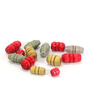 May include: A collection of colorful paper beads in shades of red, gray, and beige. The beads are cylindrical and have a slightly textured surface.