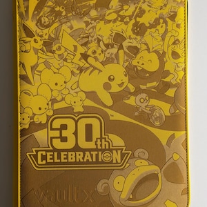 May include: A yellow zippered trading card binder featuring a monochromatic graphic print of various creatures. The front cover displays the text 30th CELEBRATION and the brand name VaultX embossed at the bottom. The design includes multiple characters.