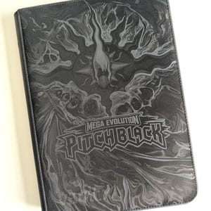 May include: A rectangular black trading card binder featuring a dark, swirling abstract graphic pattern. The cover displays the text MEGA EVOLUTION PITCH BLACK in a stylised font, with the brand name Vault X printed in smaller letters at the bottom.