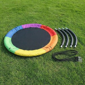 May include: A round, rainbow-colored swing seat with a black center. The swing has a colorful fabric border and comes with curved metal support bars and black rope with metal hooks. The swing is shown on a green grassy surface.