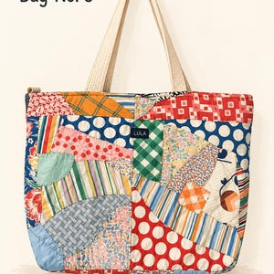 May include: A quilted tote bag featuring a patchwork design of various colorful fabrics including polka dots, stripes, and floral patterns. The bag has two light-colored handles and a small black label with the text LULA. The text Bag No. 3 is visible.