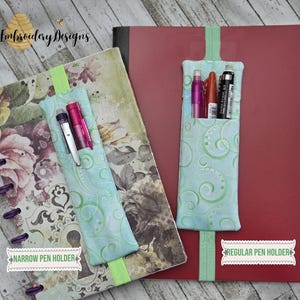 May include: Two fabric pen holders with green and blue swirl patterns. The holder on the left is labeled "Narrow Pen Holder" and the holder on the right is labeled "Regular Pen Holder".