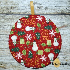 K&ouml;nnte beinhalten: Ein runder, roter Weihnachtsschmuck mit einem goldenen Band zum Aufh&auml;ngen. Das Ornament zeigt ein sich wiederholendes Muster aus Schneem&auml;nnern, Schneeflocken, Weihnachtsb&auml;umen und Geschenkboxen. Das Wort "JOY" ist ebenfalls enthalten.