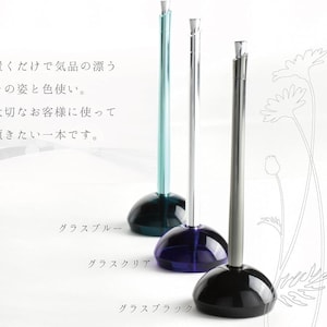 以下が含まれることがあります： 水色、シルバー、黒の3つのエレガントなガラスホルダー。それぞれ丸みを帯びたベースと細い垂直のステムがあります。画像内のテキストは「大切なお客様に使って」と書かれています。