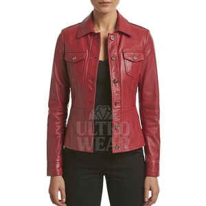 Könnte beinhalten: Rote Lederjacke mit Kragen, Knopfleiste und zwei Brusttaschen. Die Jacke hat lange Ärmel und eine taillierte Passform. Der Markenname "ULTRO WEAR" ist auf dem unteren Teil der Jacke sichtbar.