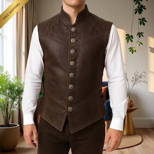Op de afbeelding: Een bruin leren vest met een hoge kraag en knoopsluiting. Het vest heeft een gewatteerd patroon op de schouders en wordt gedragen over een wit overhemd met lange mouwen. De kleur van het vest is donkerbruin.