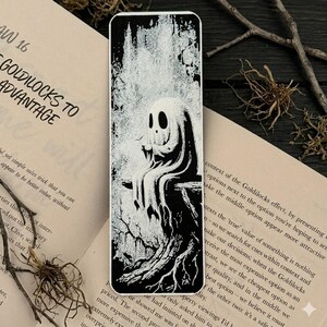 May include: A rectangular bookmark featuring a high-contrast black and white illustration of a small, hooded ghost figure sitting on a gnarled tree branch. The artwork uses detailed ink-style textures to depict the ghost and the surrounding forest.