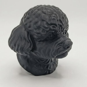 May include: A matte black 3D printed sculpture of a poodle head featuring detailed curly fur texture, floppy ears, and a distinct snout. The object is rendered in a solid dark colour with visible layer lines from the printing process throughout.