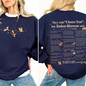 May include: Navy blue sweatshirt with a white crew neck collar. The front features a gold dragon graphic. The back of the sweatshirt has text that reads "They said 'I Love You' but Xaden Riorson said..." and a list of quotes.